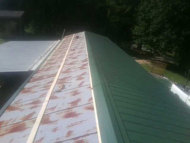 Old rusted panels beside newly installed green metal roofing — Wind Damage Roof Repair by Roofing Brothers in Starford