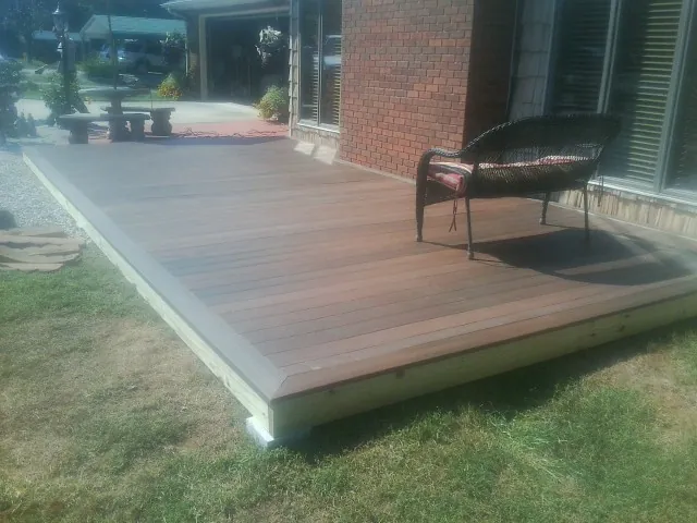 New wood deck and wicker chair beside a brick house in Starford