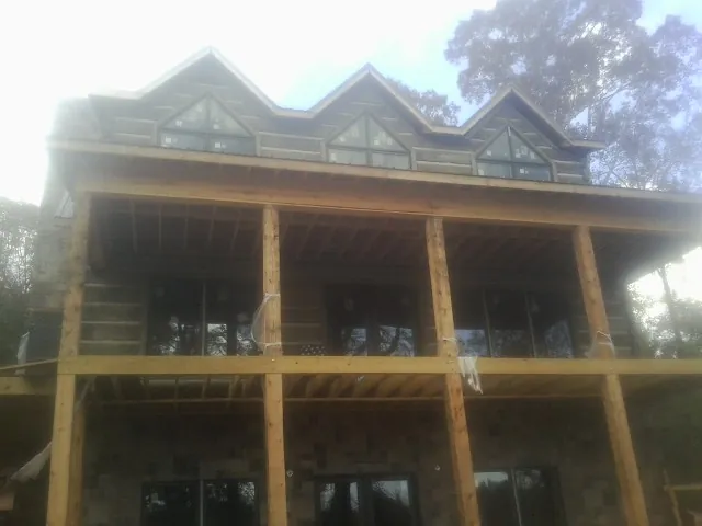Dormers and porch framing on a large log home under construction — Roof Coating work by our crew in Starford
