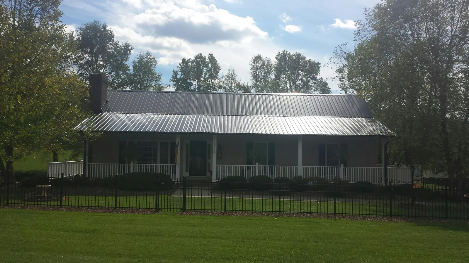Gray metal roof on a brick ranch with a full width front porch — Gutter Guard Installation work by our crew in Starford