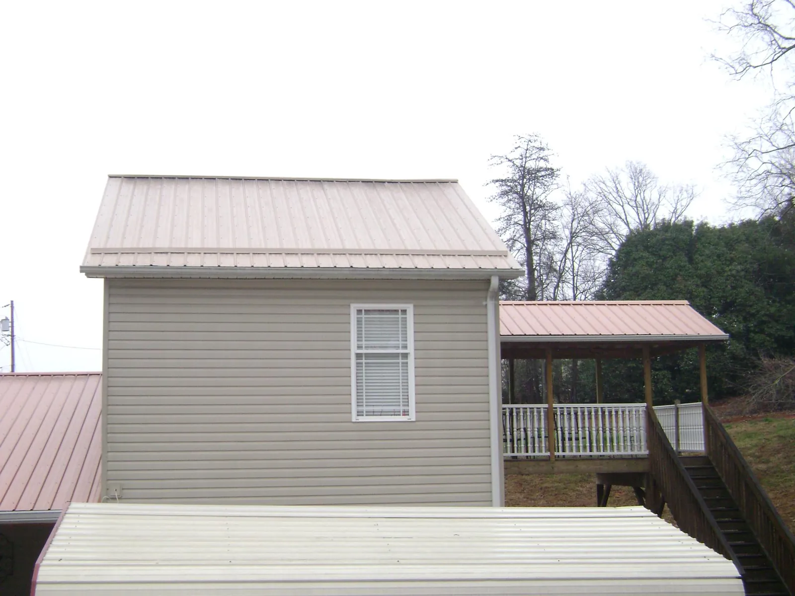 Tan metal roofs on a two story addition and attached porch, from a Roof Replacement job in Starford