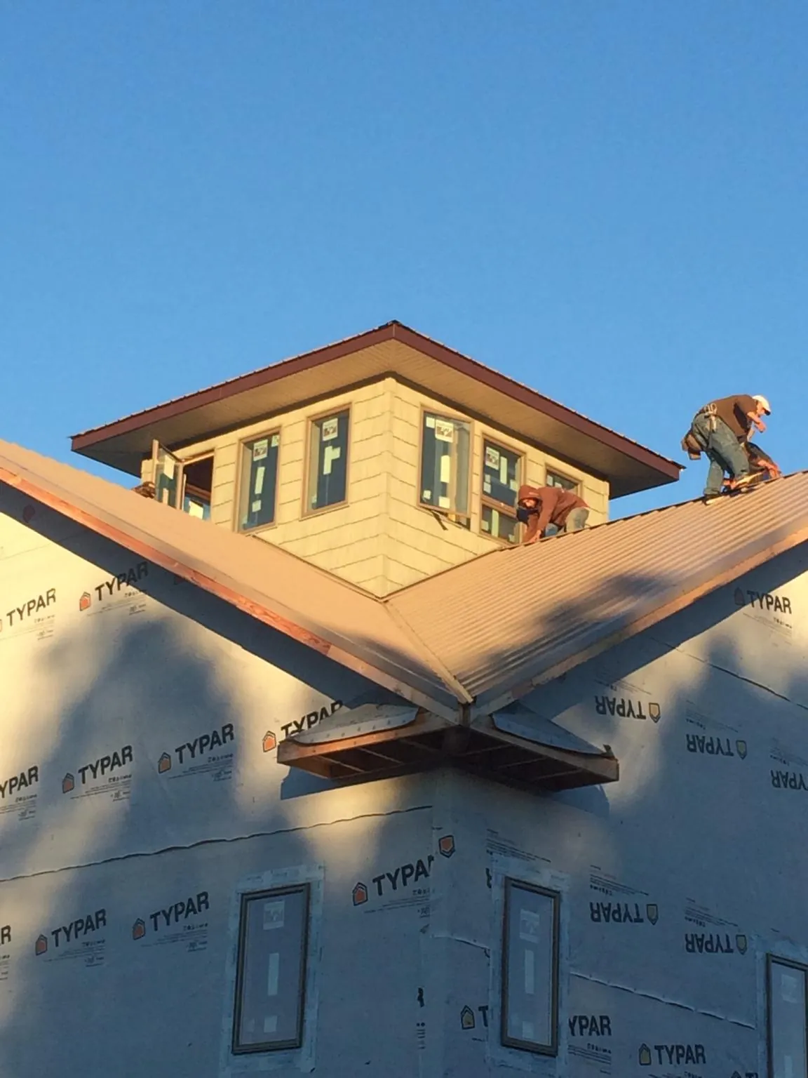 Roofers working around a rooftop cupola on a new metal roof at sunset — Roof Waterproofing in Starford by Roofing Brothers
